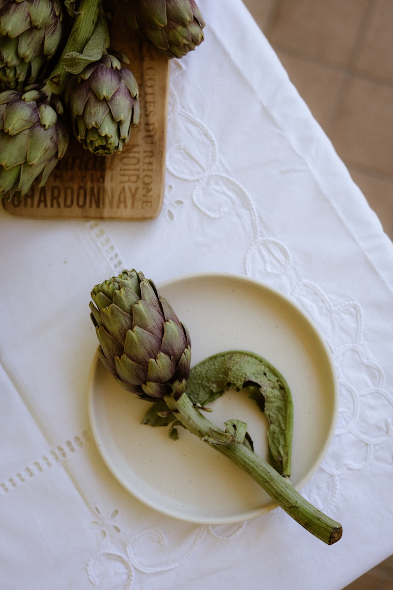 Artichokes are arranged on a white tablecloth.